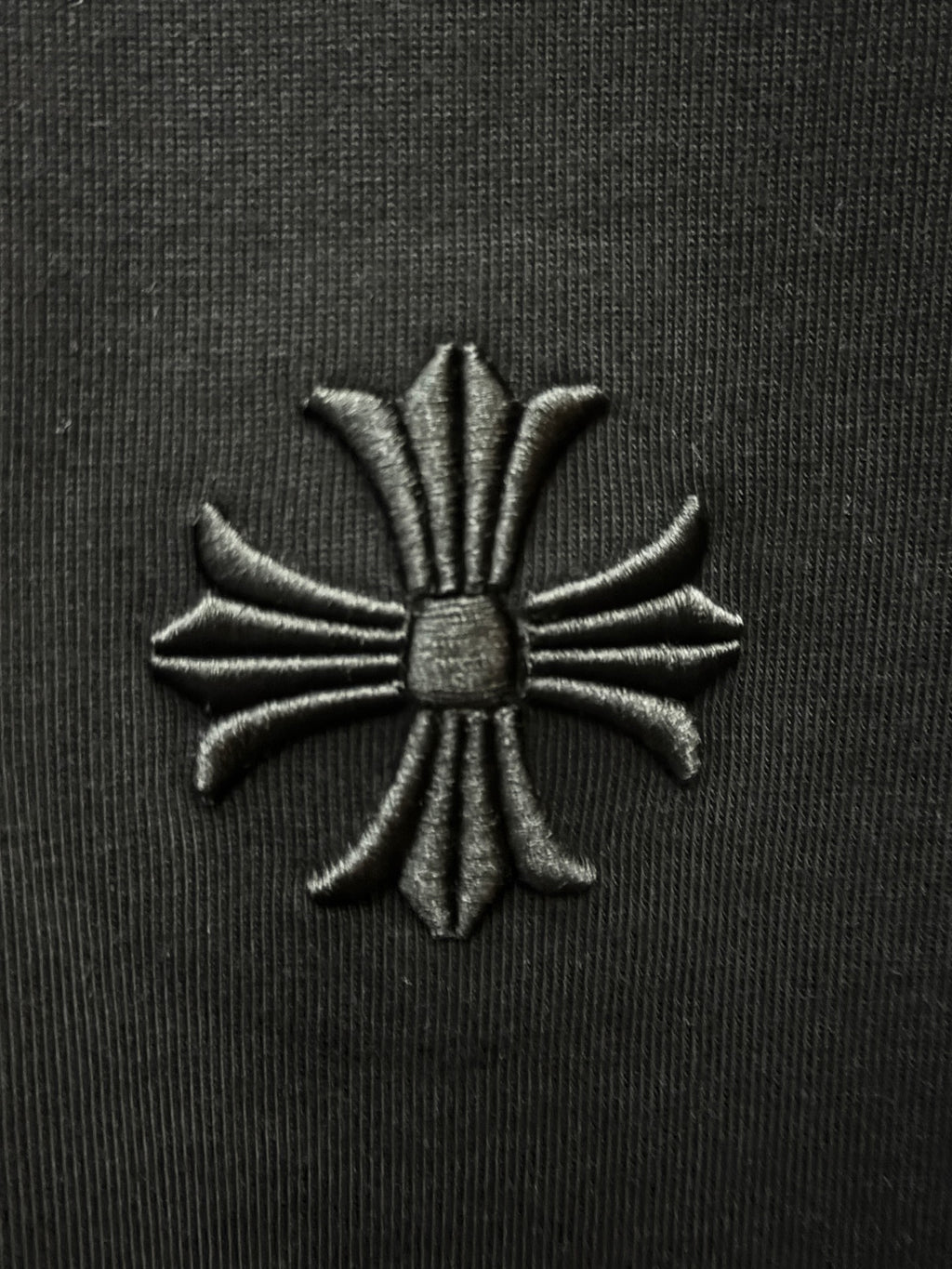 Embroidered floral cross patch on black fabric