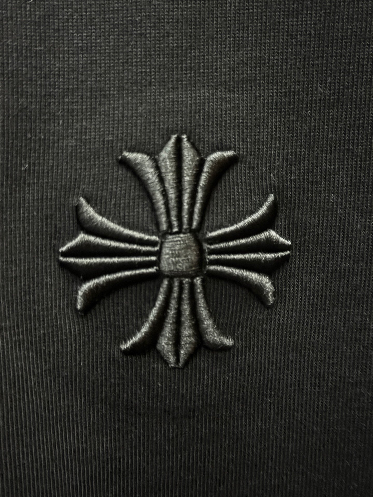 Embroidered floral cross patch on black fabric