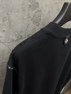 Black crewneck T-shirt close-up of shoulder and sleeve edge with stud trim