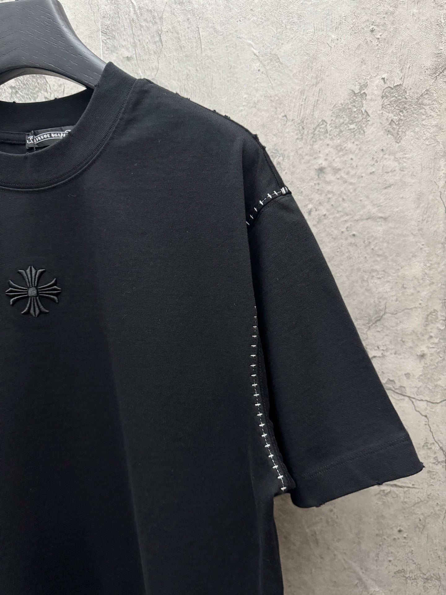 Black long-sleeve style? no—short-sleeve T-shirt with chest emblem and sleeve stud trim