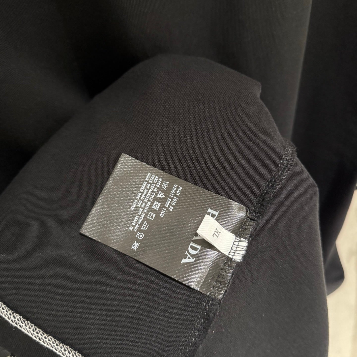 Prada fabric tag on black short-sleeve T-shirt side seam