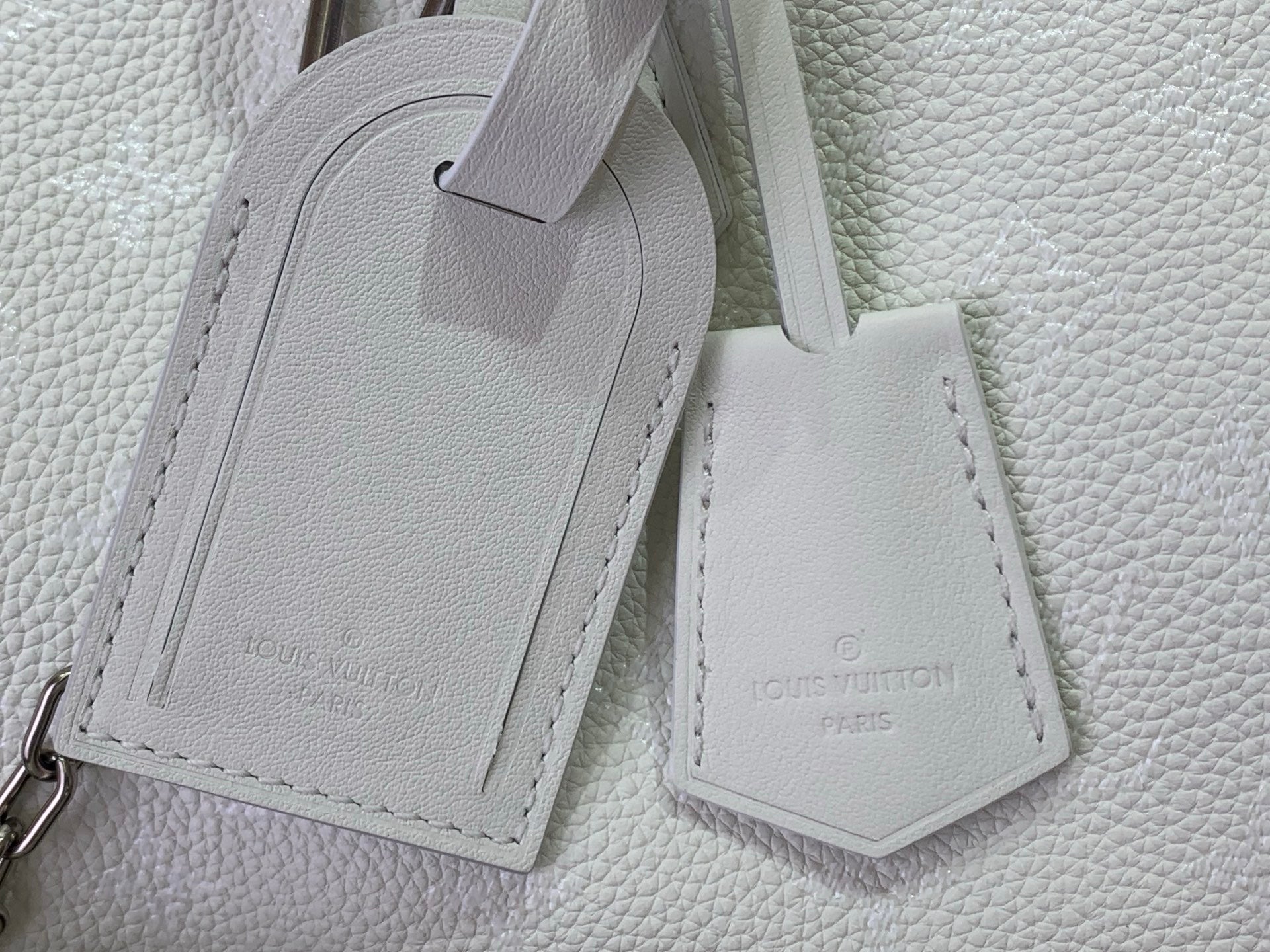 White leather bag strap ends with stitched label tags
