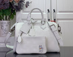 White leather handbag with top handles, crossbody strap, and front charm patch