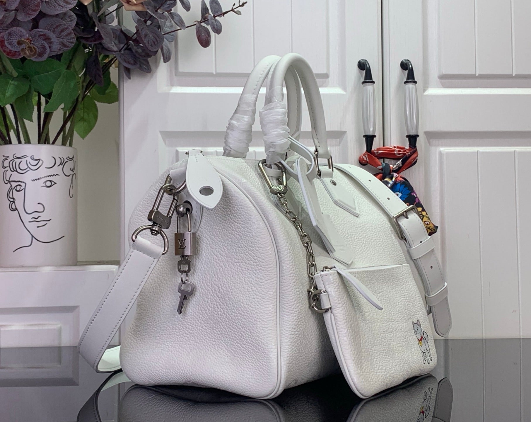 White leather handbag with chain strap and crossbody strap, front charm detail