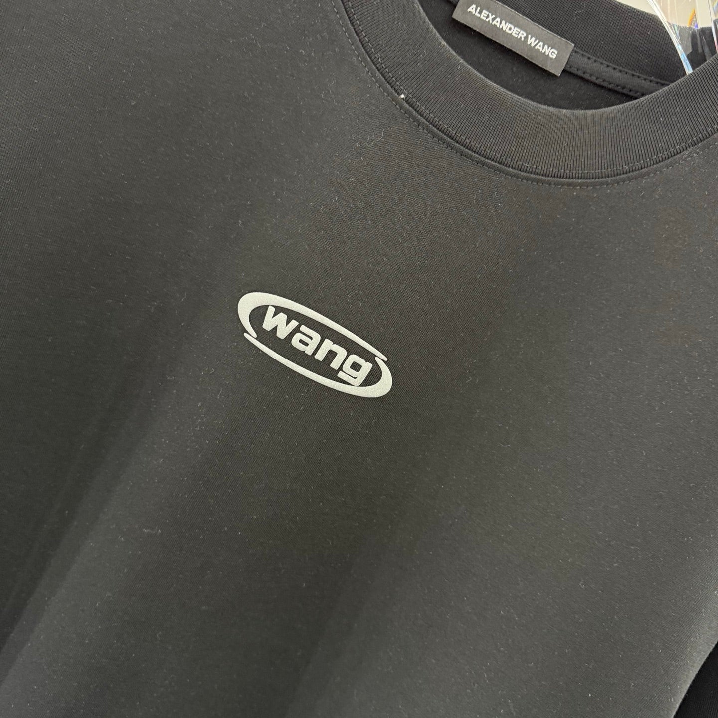 Black T-shirt fabric texture with wang logo, close-up
