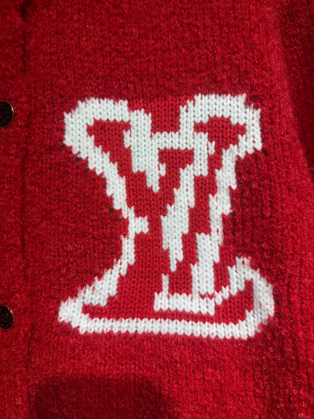 Red cardigan chest close-up featuring a large white LV-style intarsia logo