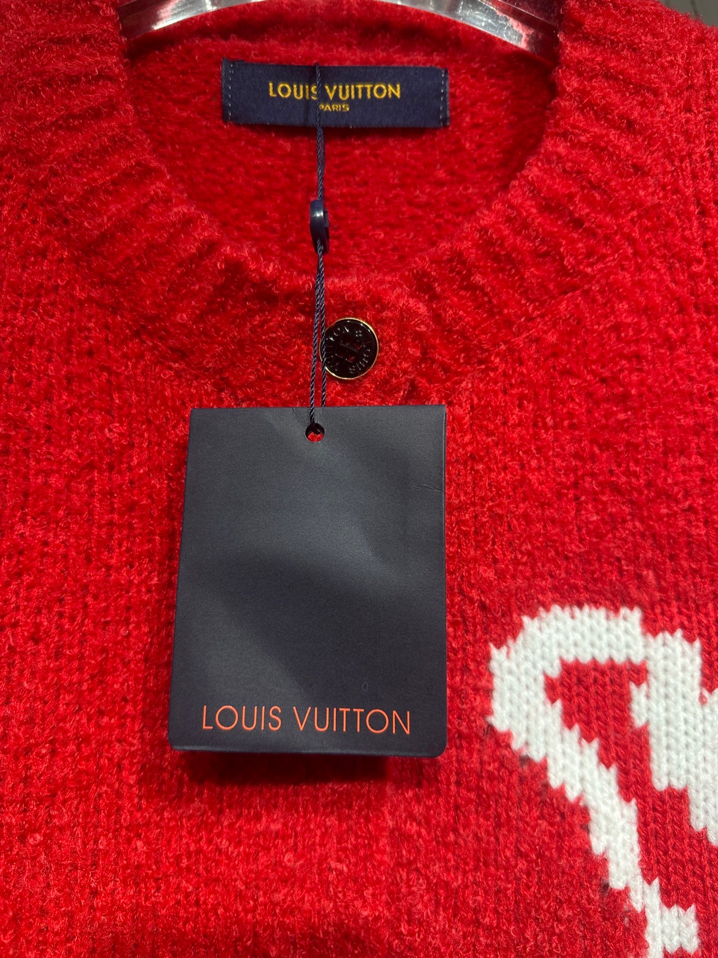 Red cardigan collar close-up with interior brand tag and small black button