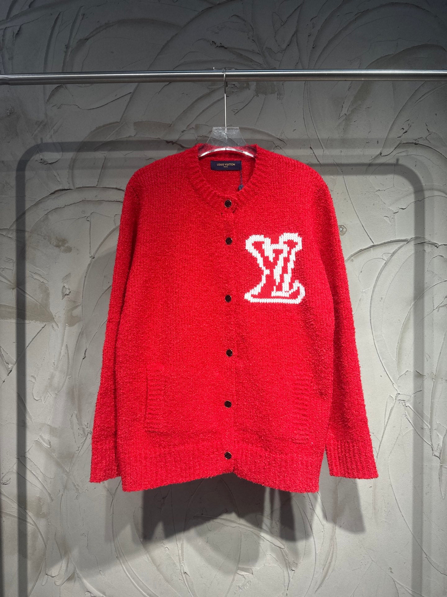 Red button-up cardigan with large white LV-style logo on the chest