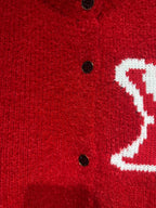 Red cardigan close-up of black buttons and partial white LV-style logo