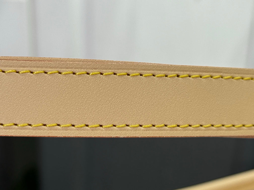 Close-up of tan leather edge with yellow stitching on a designer tote