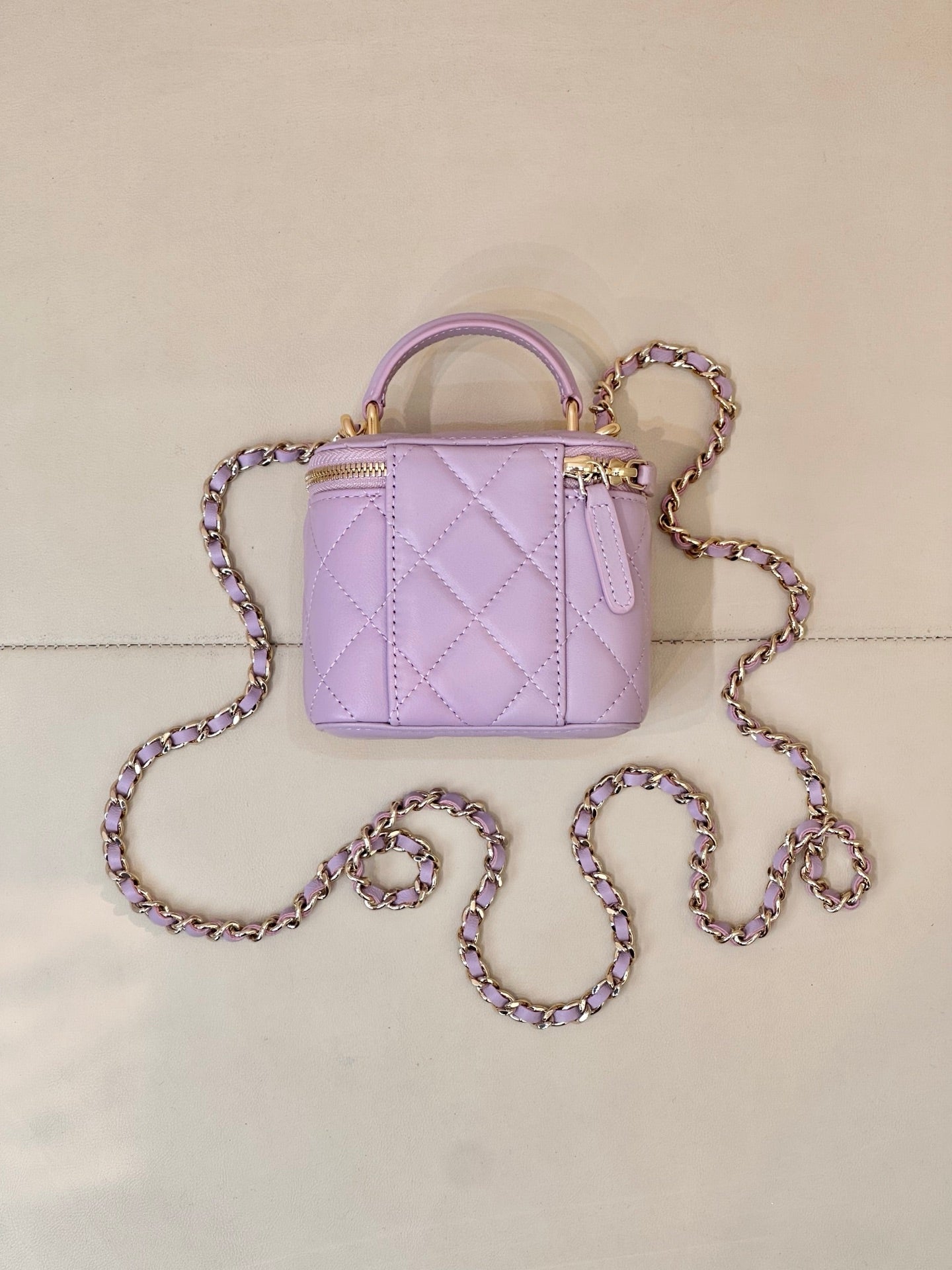 Chanel lavender quilted mini handbag with top handle and long chain strap in loops