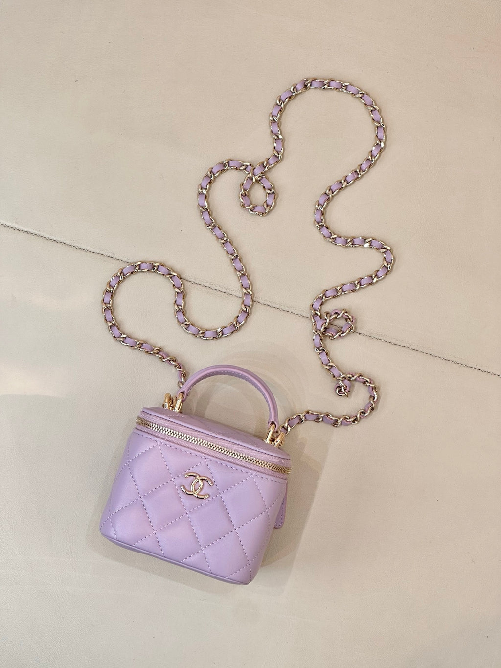 Chanel lavender quilted mini bag with top handle, long chain strap, and zip closure