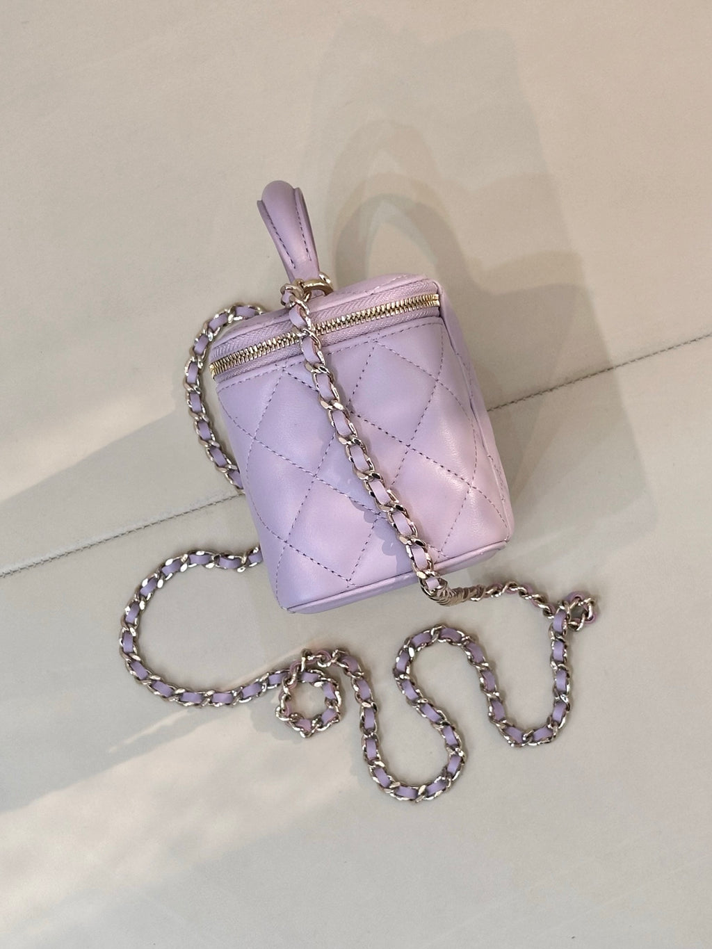 Lavender Chanel quilted bag with gold-tone zipper, top handle and chain strap
