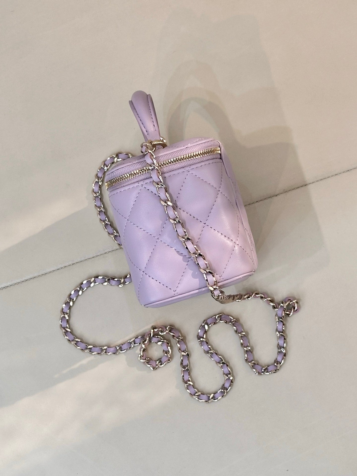 Lavender Chanel quilted bag with gold-tone zipper, top handle and chain strap