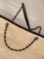 Beige woven tote bag corner view with chain handles and black top trim