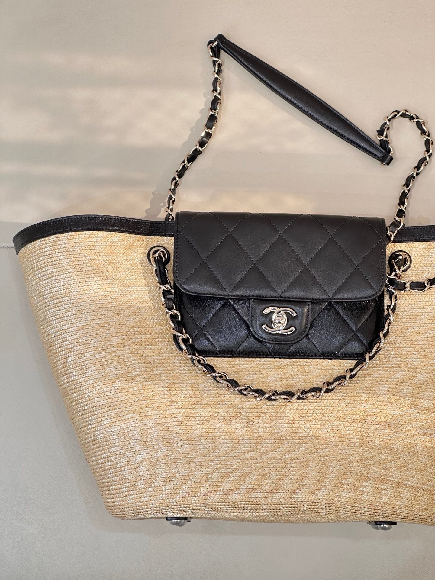 Beige woven tote bag with black quilted flap and chain shoulder strap