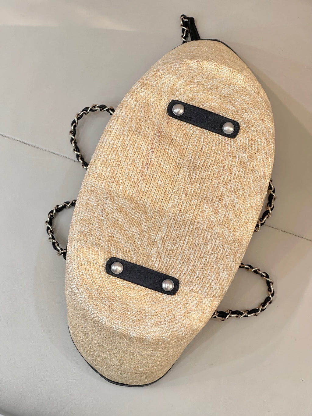 Beige textured crossbody pouch with black strap buttons and chain shoulder strap