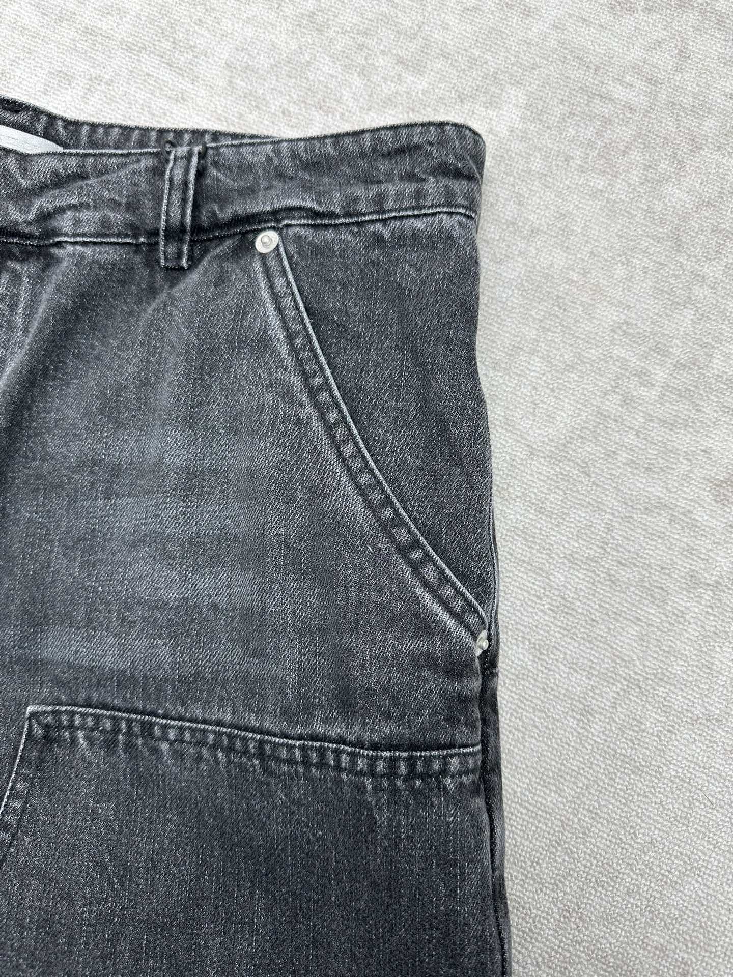 Denim pants side view with angled seam and stitched hems at the cuff