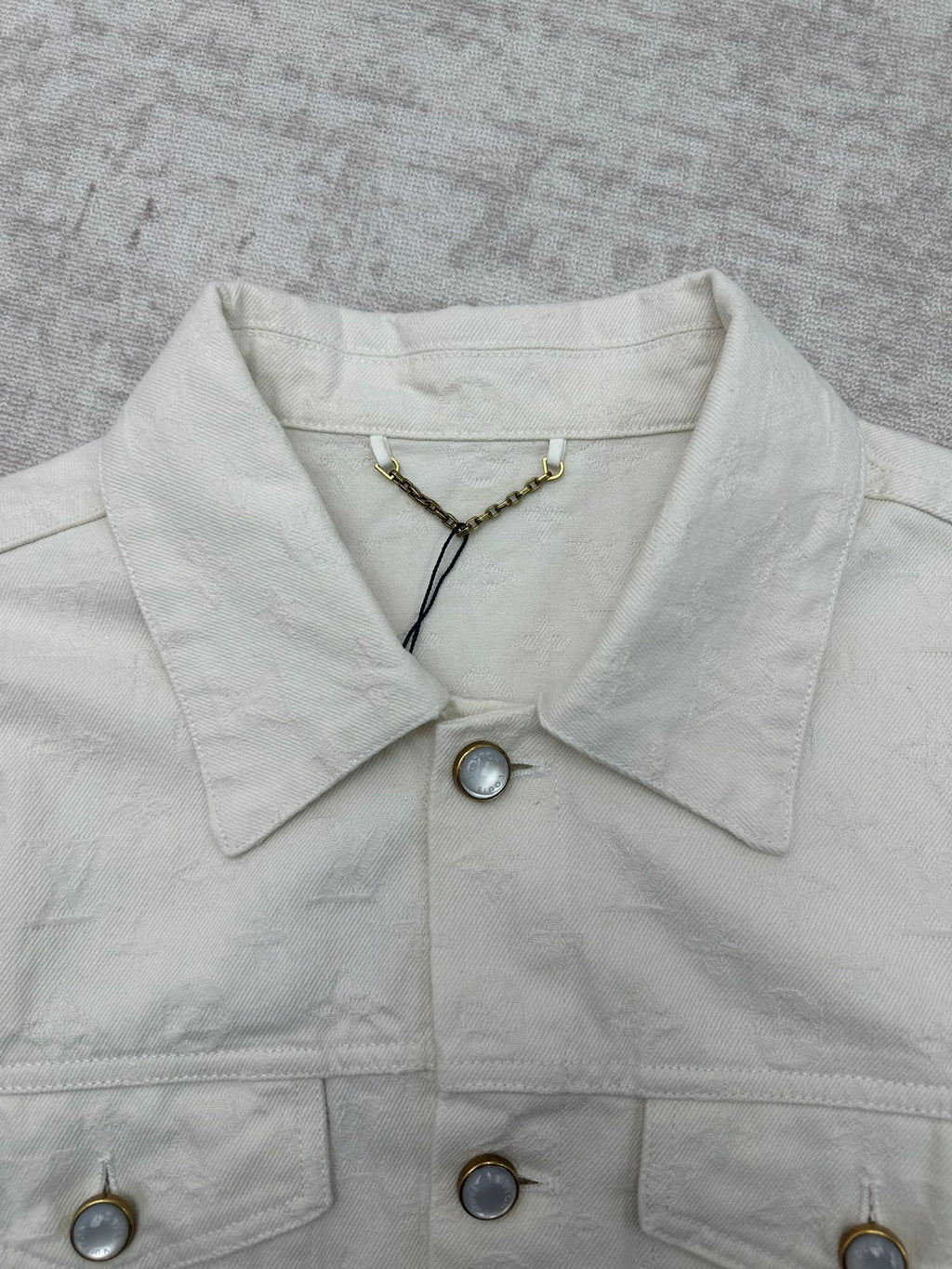 Long white jacket neckline with pointed collar, snap buttons, gold chain detail