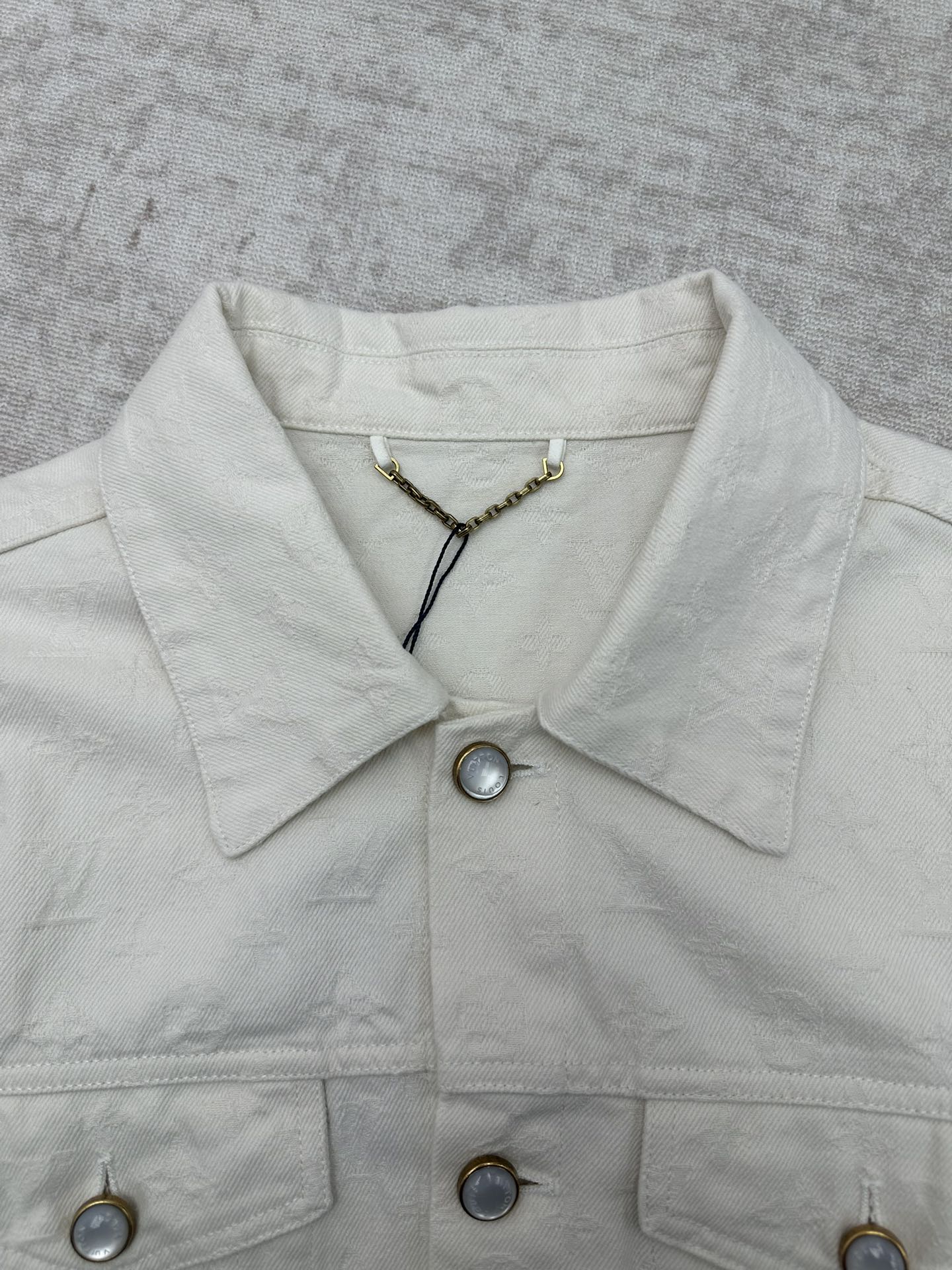 Long white jacket neckline with pointed collar, snap buttons, gold chain detail