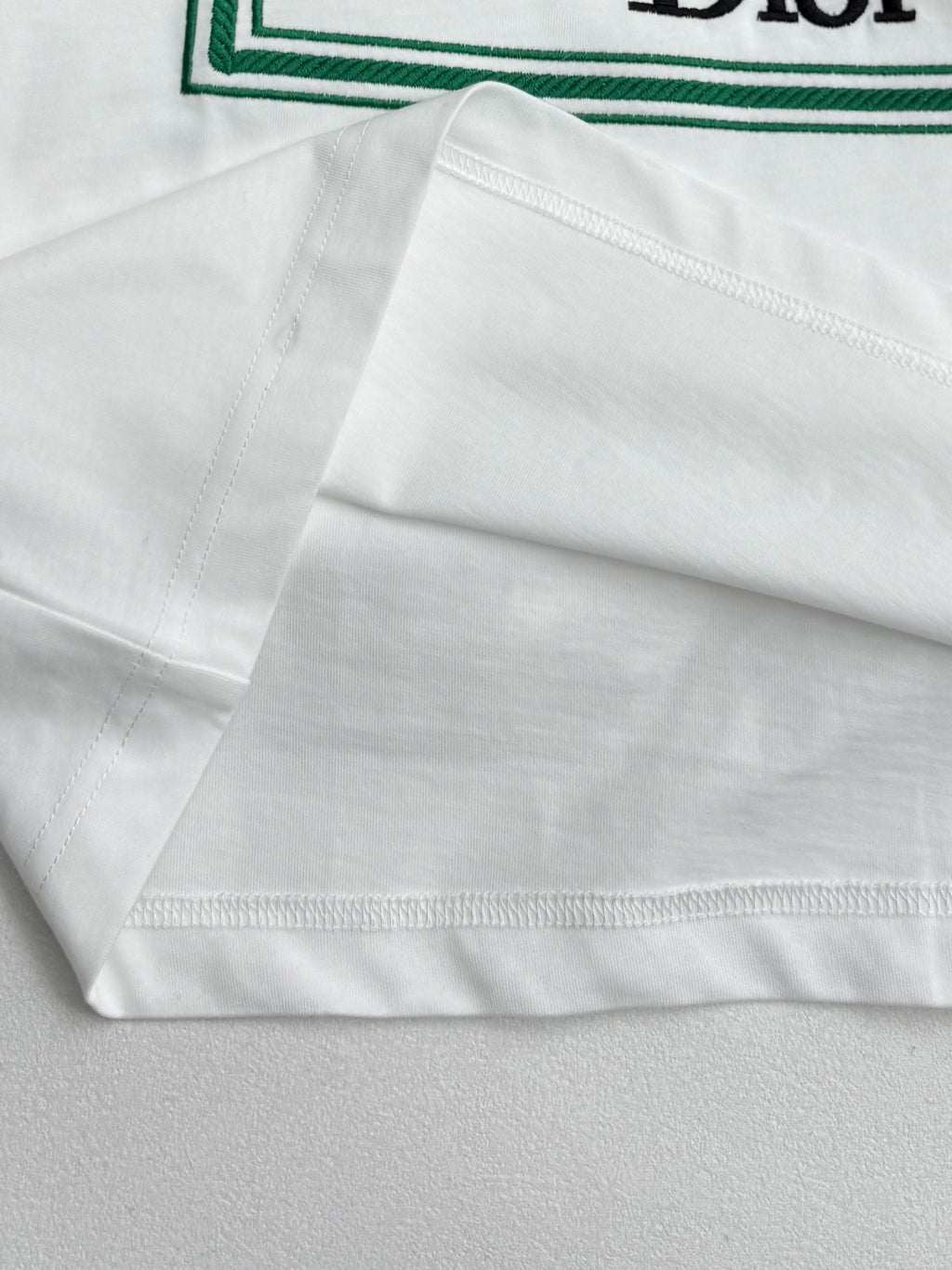 White Dior T-shirt hem with green-trim edge and stitching