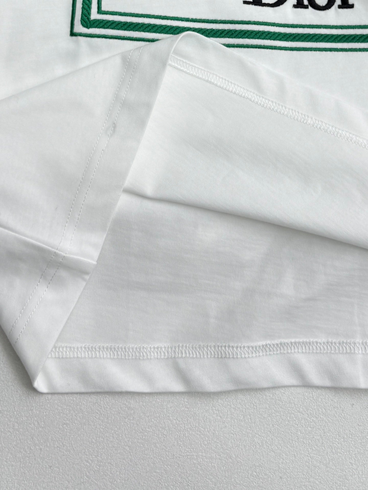 White Dior T-shirt hem with green-trim edge and stitching
