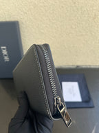 Dior small zip wallet bag close-up, textured dark leather with shiny metal zipper
