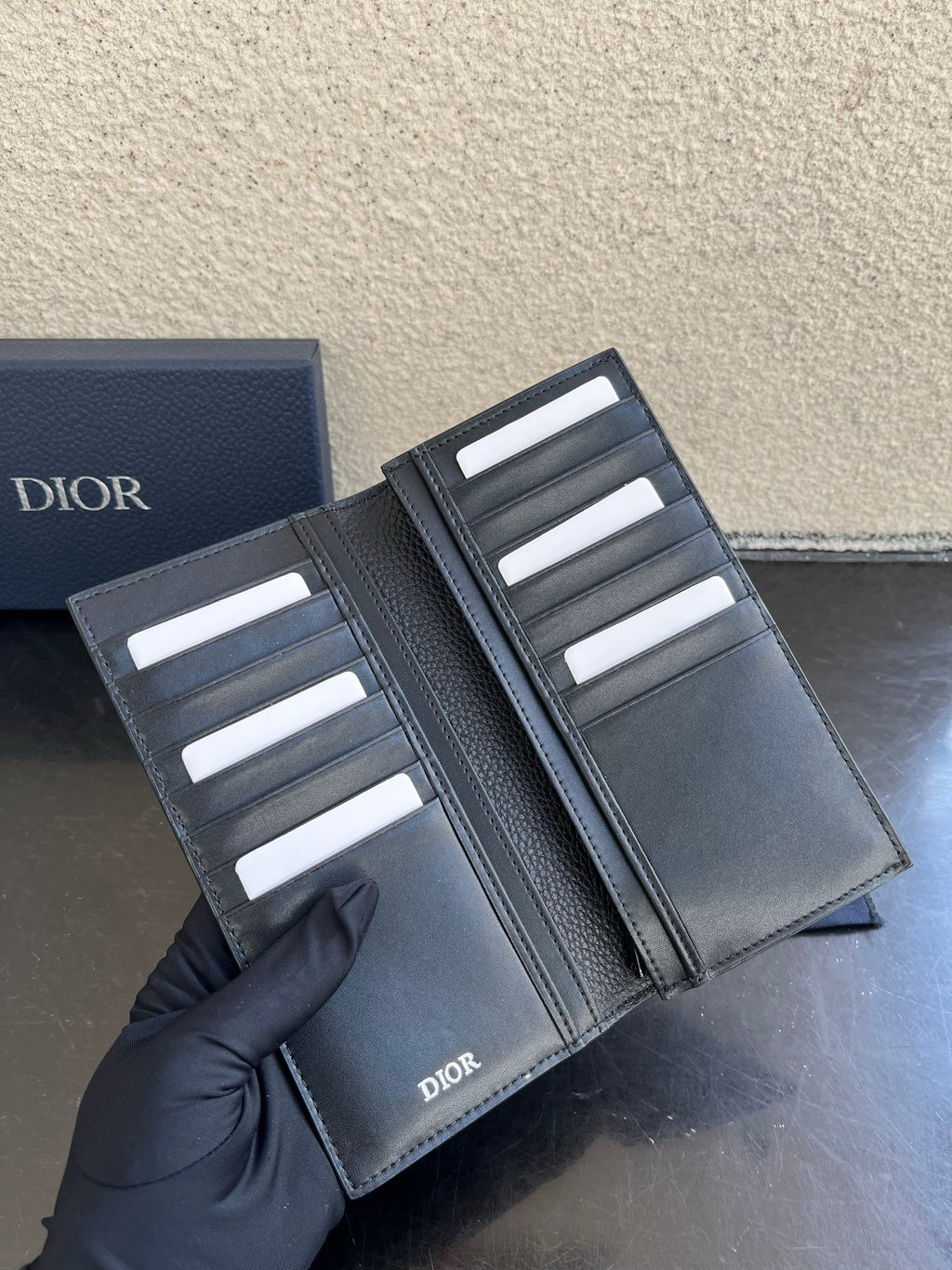 Small bag wallet-style card slots opened, dark leather with Dior logo