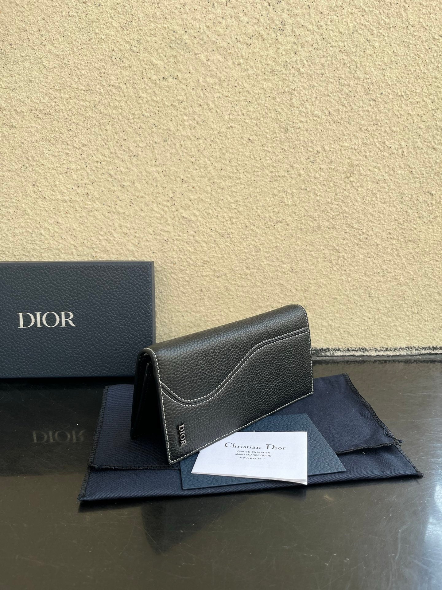 Small bag in dark gray textured leather, folded front view with Dior branding