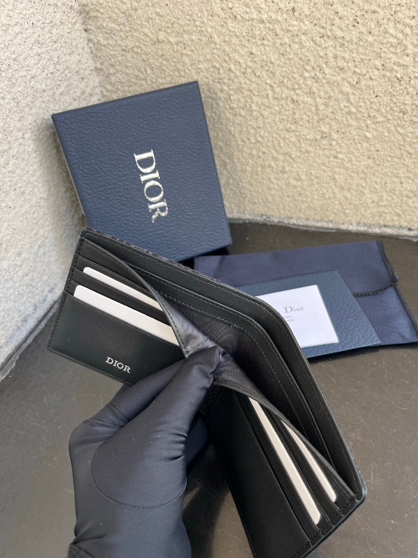 Dior small leather wallet open, dark interior with card slots and Dior logo.