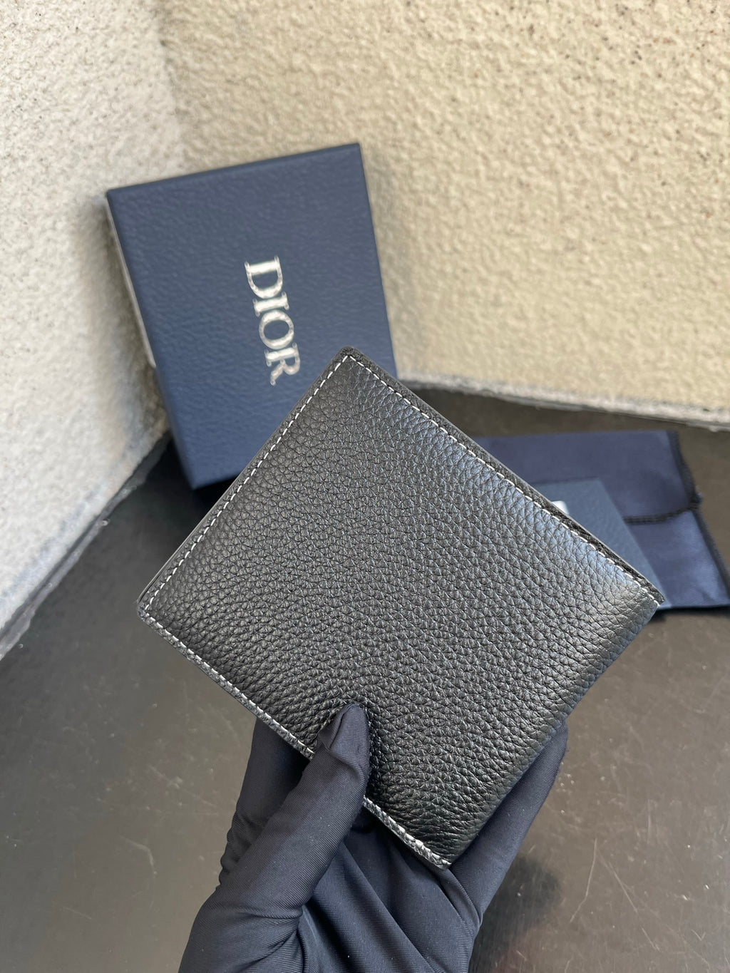 Dior small leather card wallet with flap, textured dark finish and stitched edge.