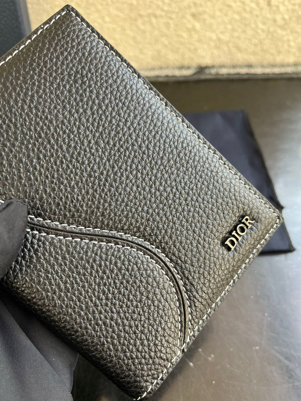 Dior small card holder bag in dark textured leather with stitched wristlet strap detail.