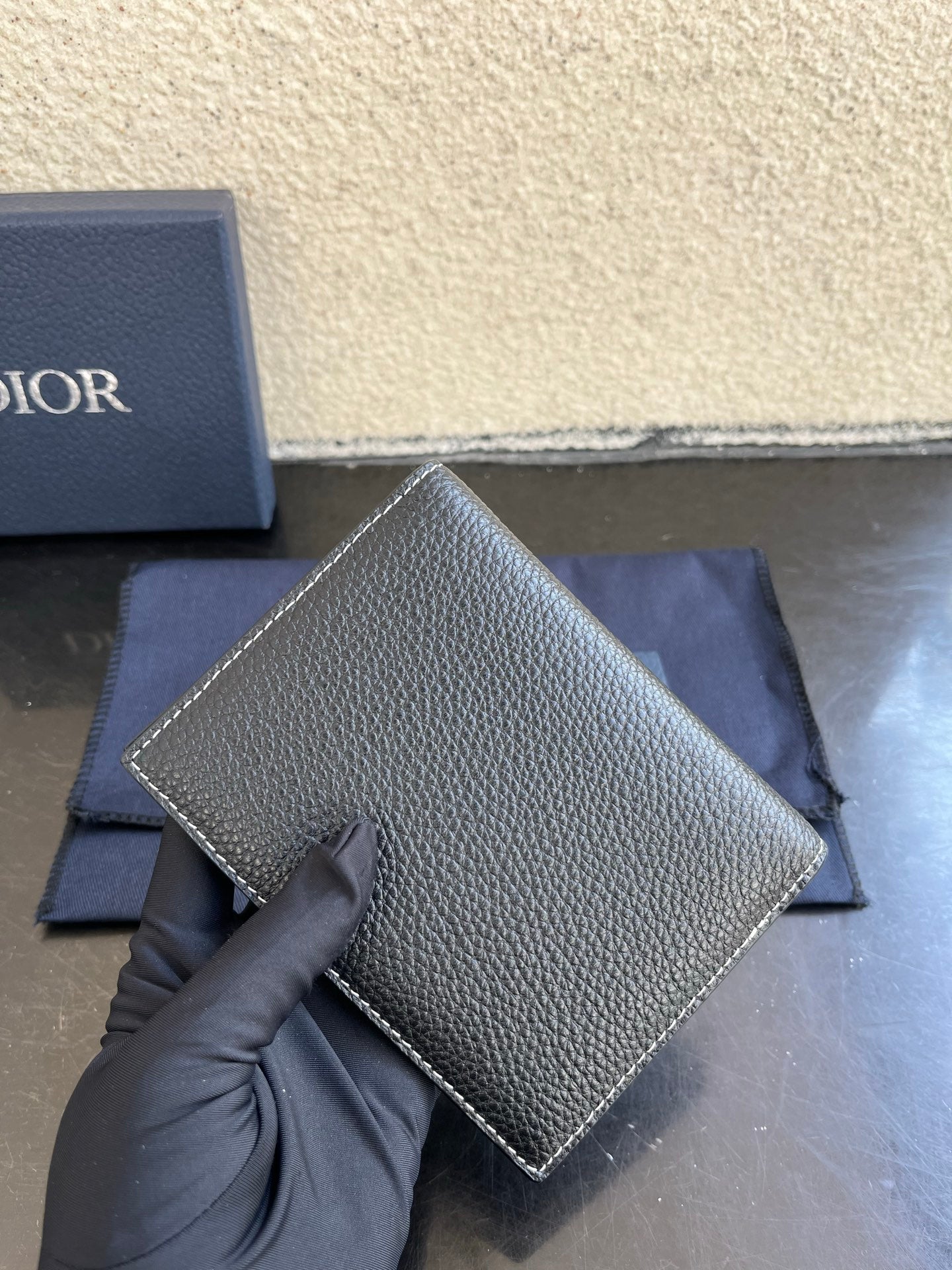 Dior card holder in dark textured leather with straight edge and logo on front.