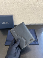 Dior card holder in dark textured leather, side view with stitched curved flap and logo.
