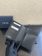 Dior card holder in dark textured leather, open view showing interior card slots.