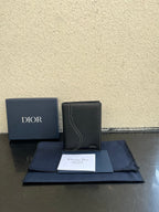 Dior card holder in dark textured leather with curved flap detail and Dior logo.