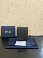 Dior card holder in dark textured leather, upright view with flap and Dior branding.