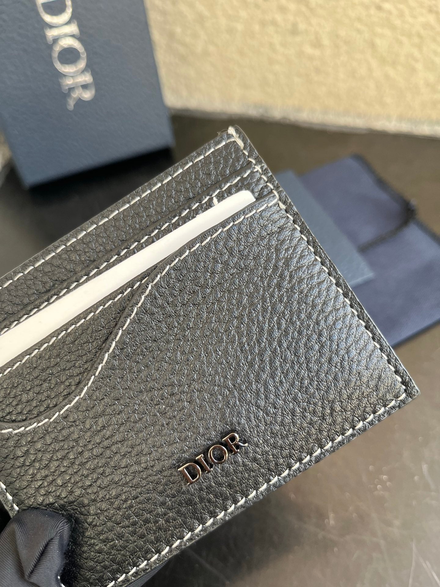 Close-up of Dior card holder stitching and logo on textured dark leather