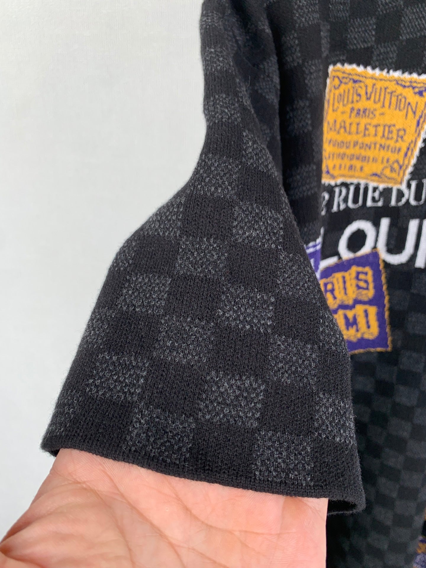 Black check short-sleeve T-shirt sleeve close-up with graphic patch at hem