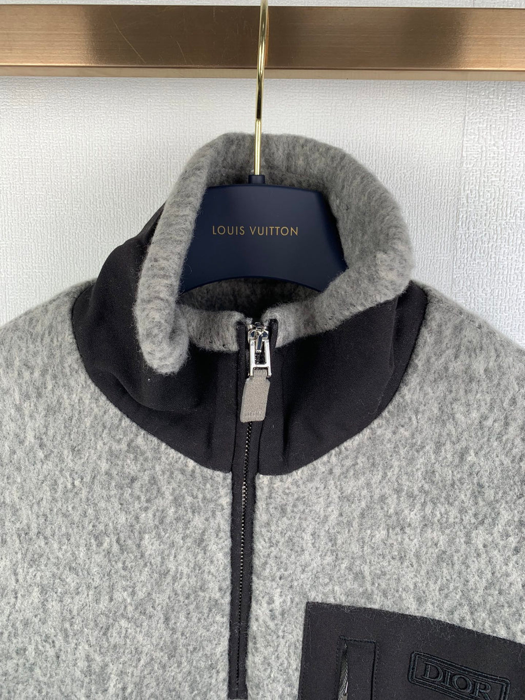 Gray zip jacket with black stand collar, front zipper, and Dior-branded pocket