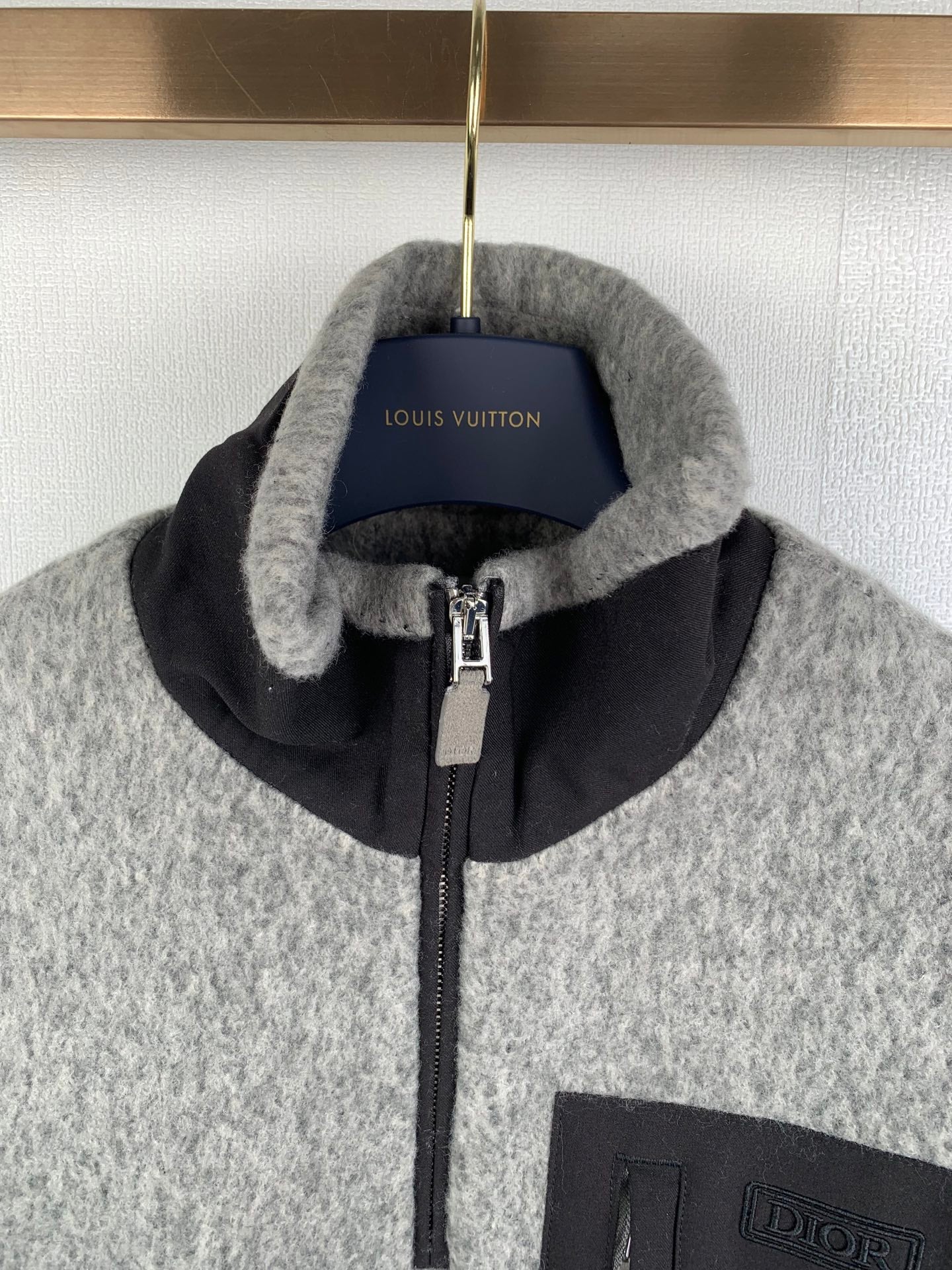 Gray zip jacket with black stand collar, front zipper, and Dior-branded pocket