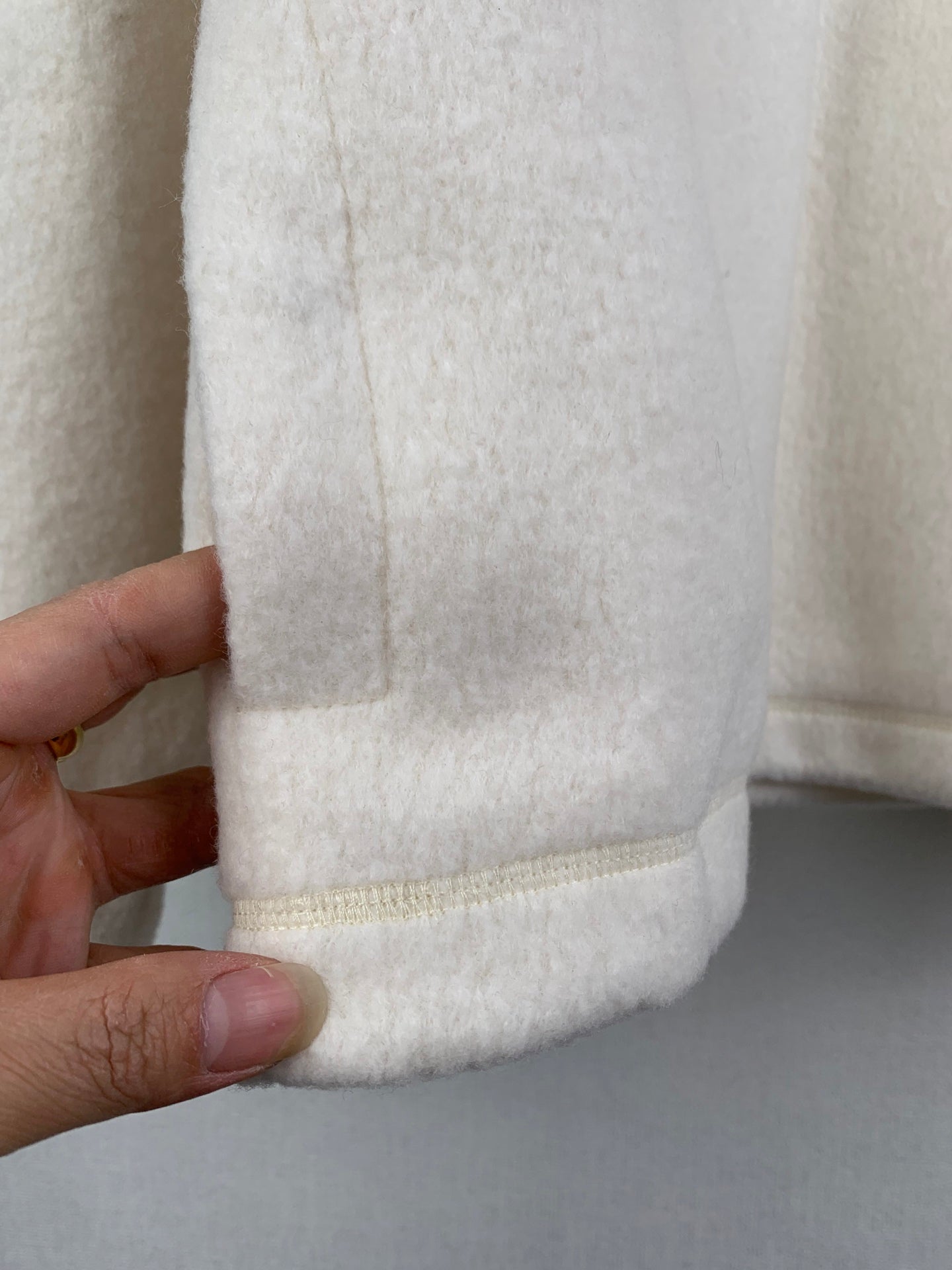 Cream fleece jacket hem with stitched band and smooth texture