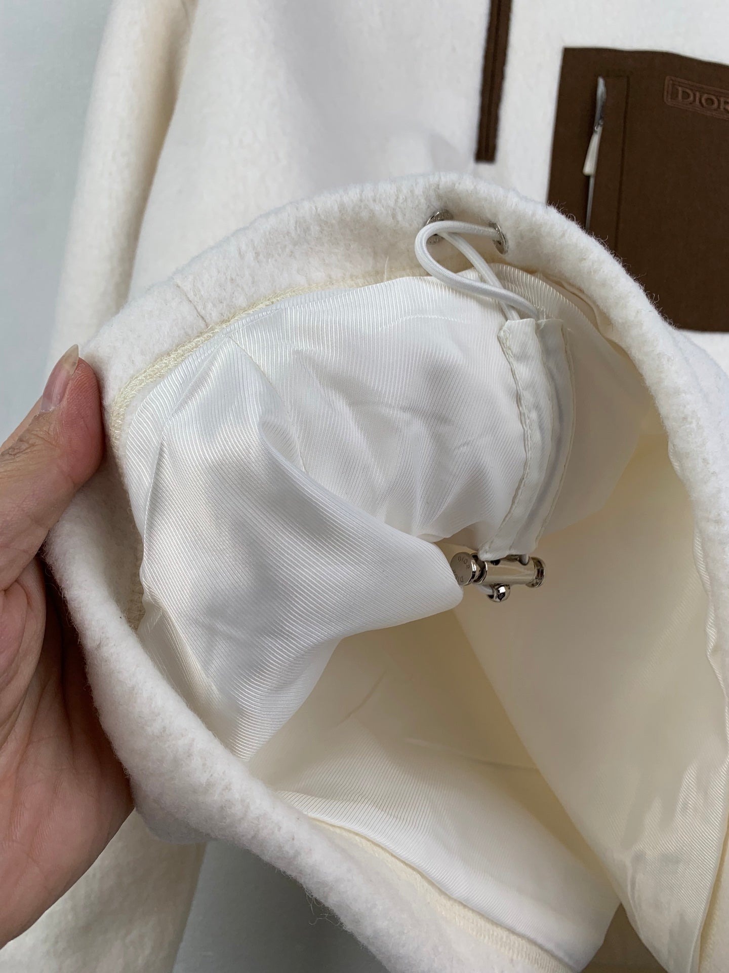 Cream fleece jacket hood lining with drawstring cord and stopper