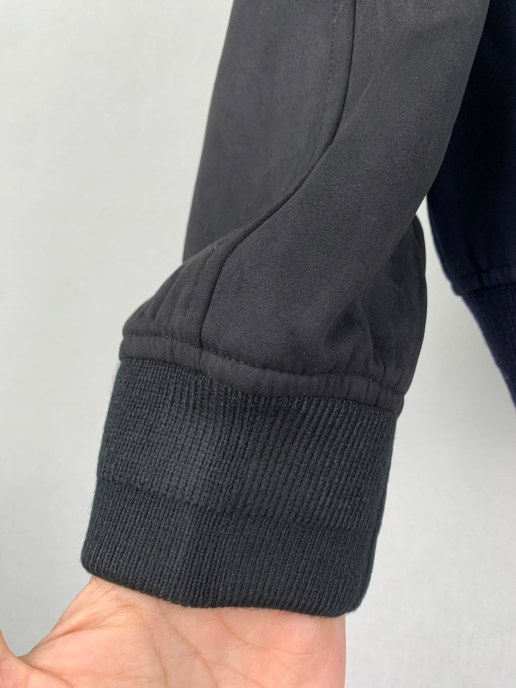 Sleeve cuff of dark navy jacket with ribbed knit hem and gray sleeve panel
