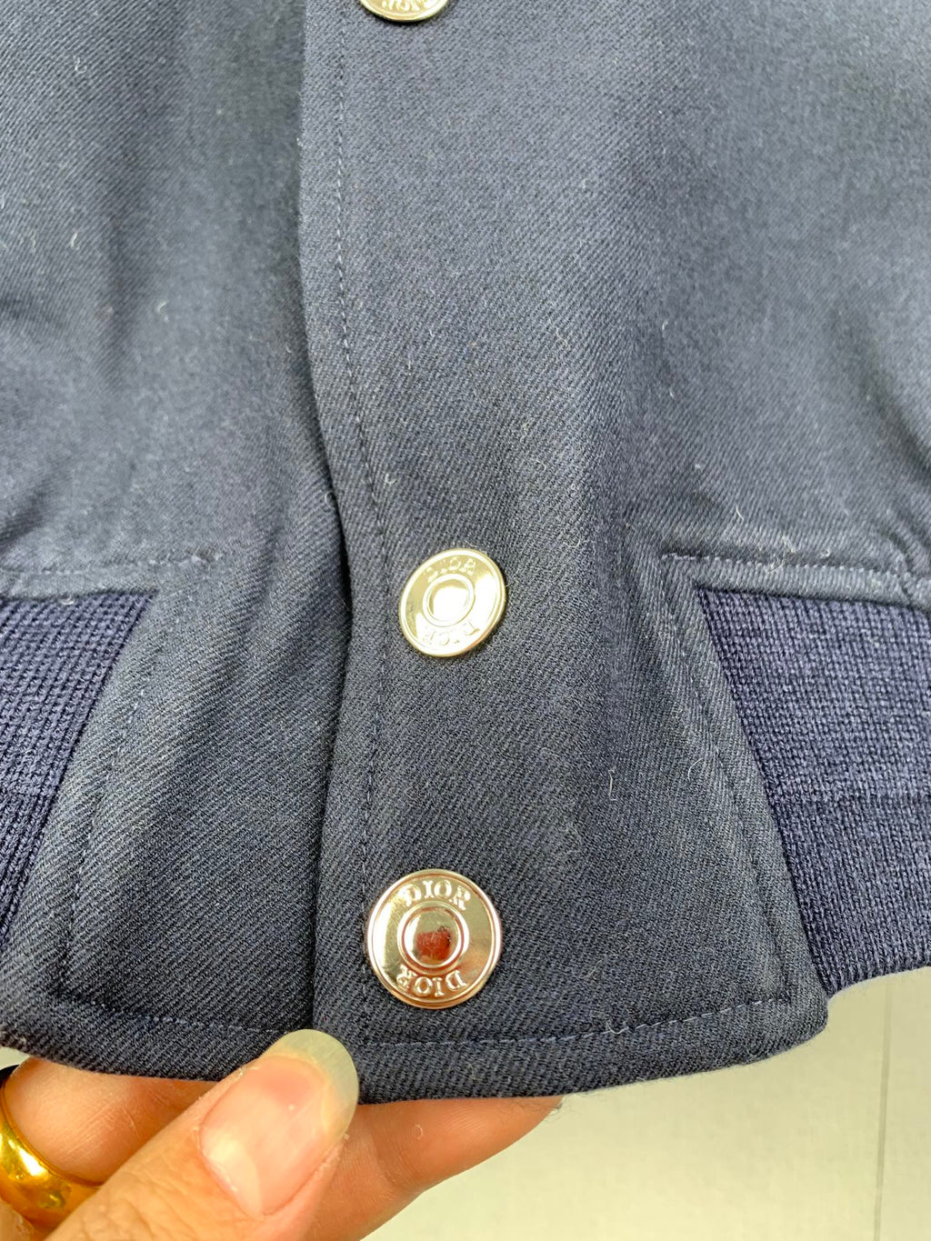 Close-up of navy jacket front with gold snap buttons and logo medallions