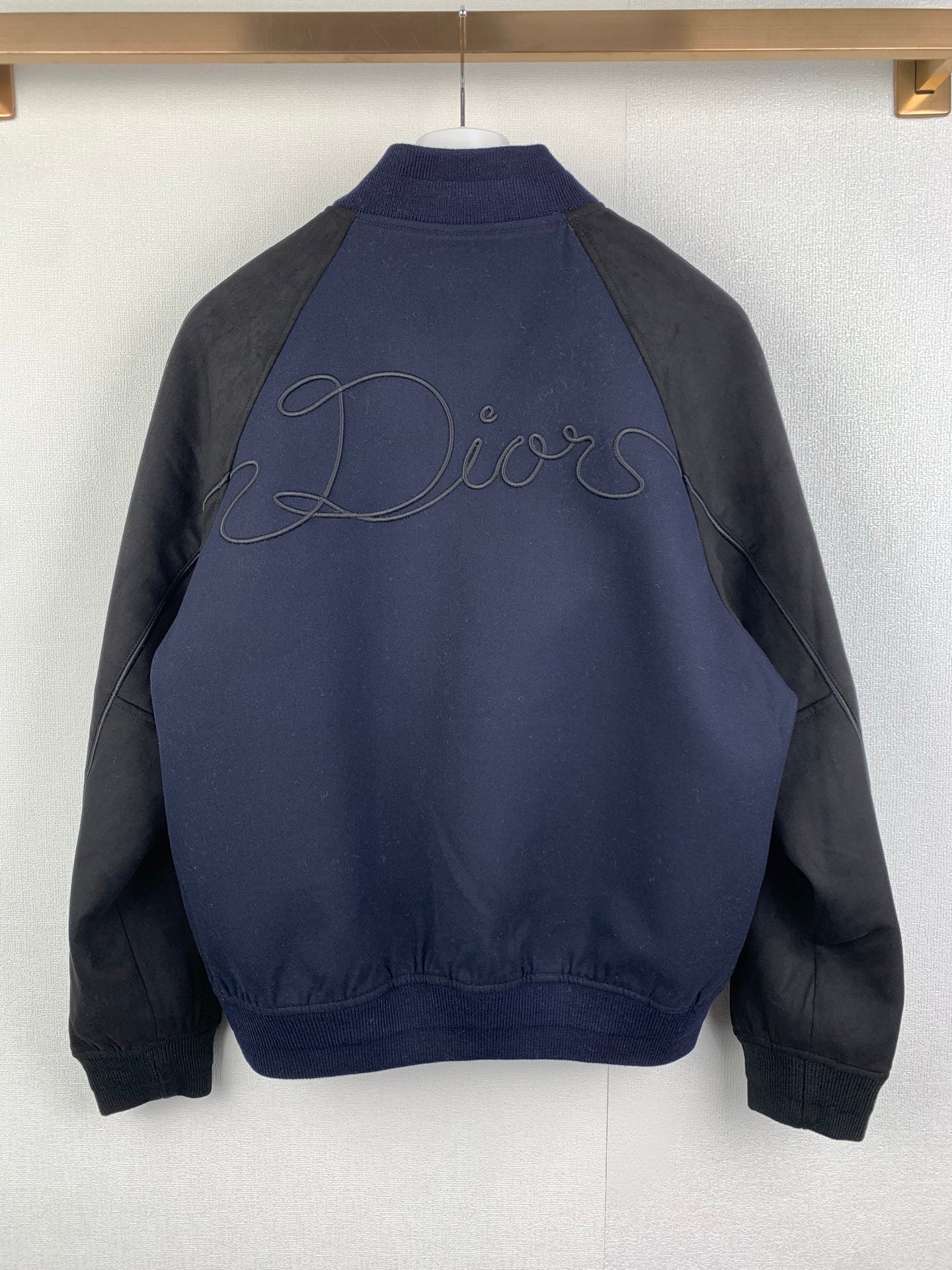 Back view of long-sleeve jacket in dark navy with gray sleeves, Dior script embroidery