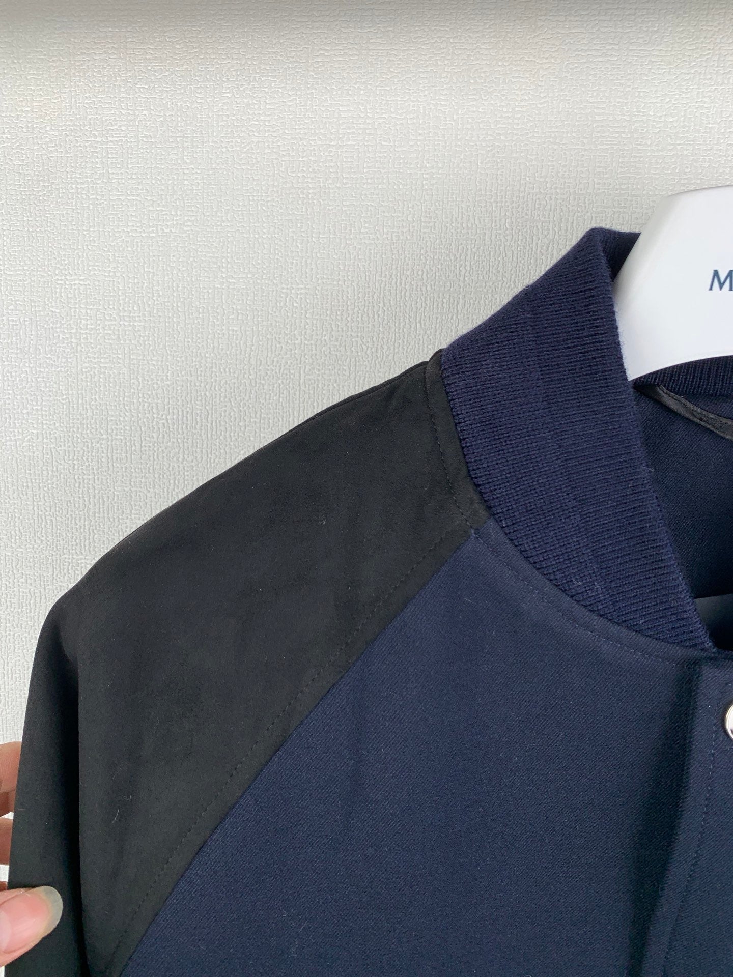 Shoulder and side panel of navy jacket with gray sleeve overlay, ribbed stand collar
