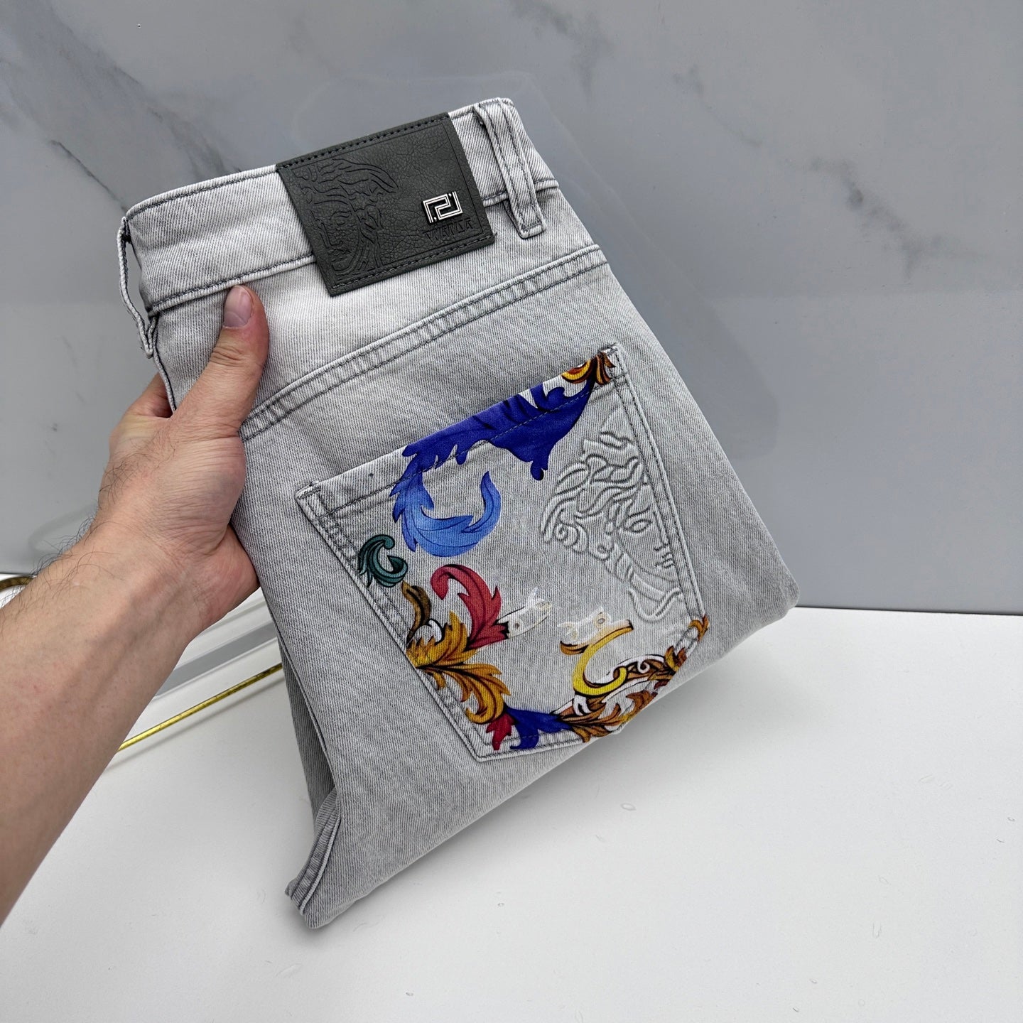 Versace denim jeans with colorful baroque-print pocket panel and logo patch on waistband