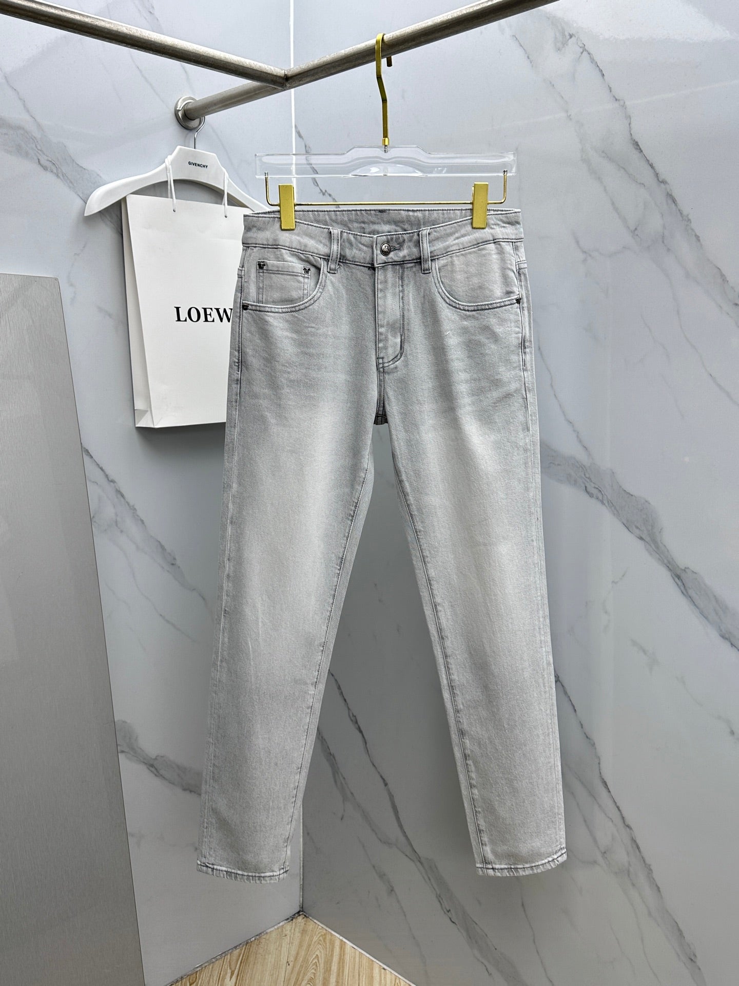 Versace light-gray denim jeans hanging on a rack, straight-leg fit