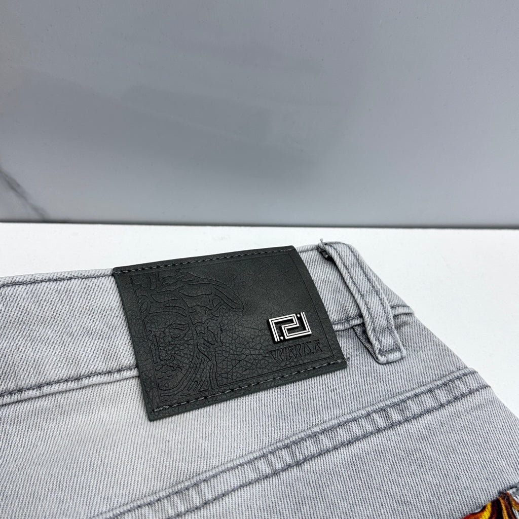 Versace denim jeans close-up of black leather logo patch on waistband